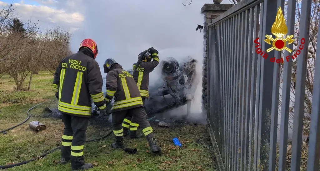 Auto contro la recinzione di una casa, cappotta e prende fuoco